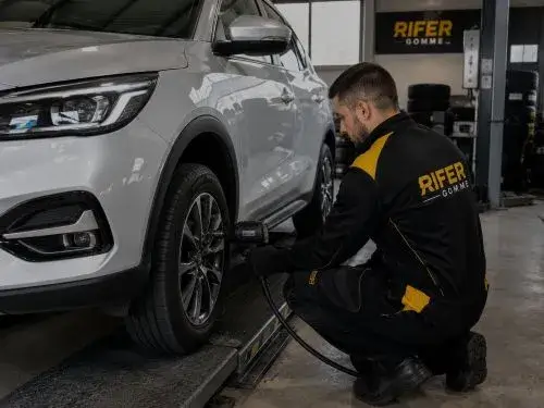 operatore di rifer gomme che sta facendo manutenzione ad uno pneumatico di un auto